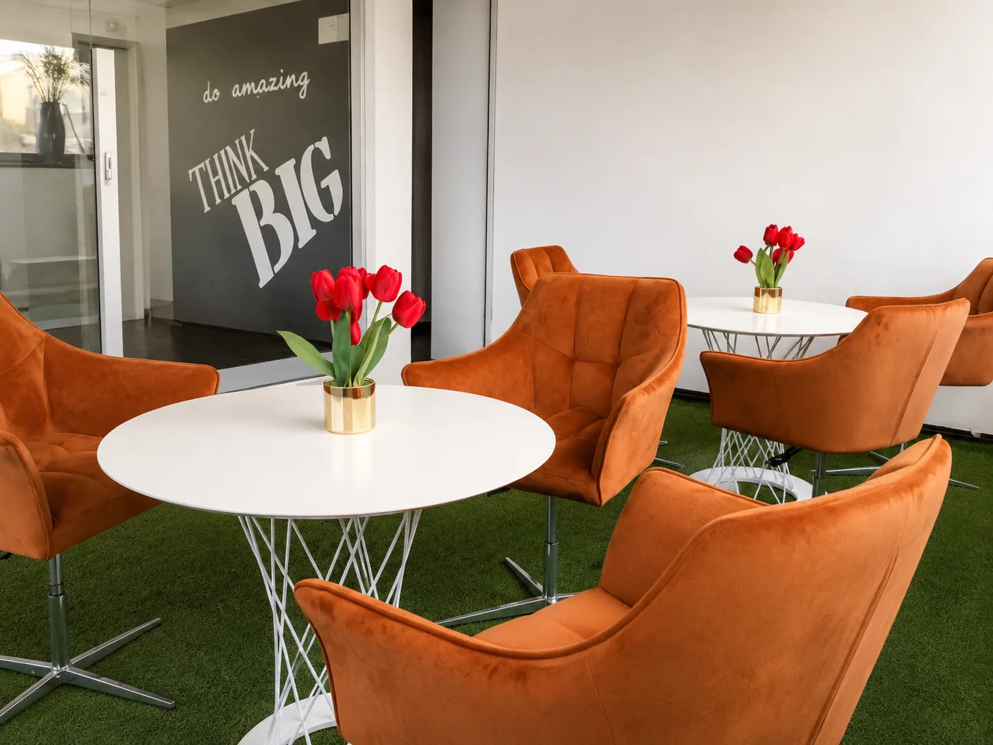 Área de coworking GBC com poltronas laranja e mesas redondas